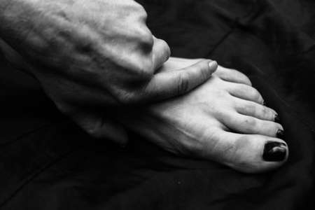 Female legs, hands. beautiful feet and palms on a black background, close-up. Black and white photography, natural light.の写真素材