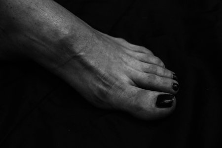 Female legs, hands. beautiful feet and palms on a black background, close-up. Black and white photography, natural light.の写真素材