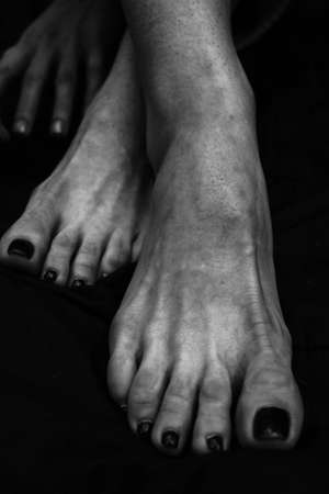 Female legs, hands. beautiful feet and palms on a black background, close-up. Black and white photography, natural light.の写真素材
