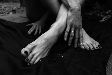 Female legs, hands. beautiful feet and palms on a black background, close-up. Black and white photography, natural light.の写真素材