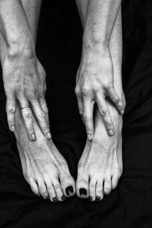 Female legs, hands. beautiful feet and palms on a black background, close-up. Black and white photography, natural light.の写真素材