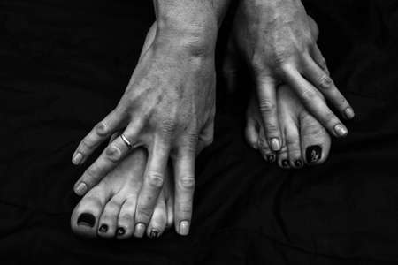 Female legs, hands. beautiful feet and palms on a black background, close-up. Black and white photography, natural light.の写真素材