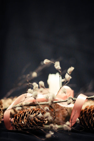 Pink Christmas decorations with candlelight, pink ribbons, twigs, dry grass, including sparkling baubles, ribbons and pine cones, on a black background.の写真素材