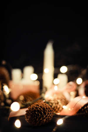 Pink Christmas decorations with candlelight, pink ribbons, twigs, dry grass, including sparkling baubles, ribbons and pine cones, garland lanterns, bokeh effect, on a black background.の写真素材