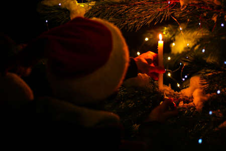 Christmas tree with gold defocused lights and silhouette of spruce branch. defocused new year background with space for text candles, man in santa hatの写真素材