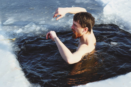young, slim, handsome, sporty man with a red beard and long hair, naked, in black shorts, diving...