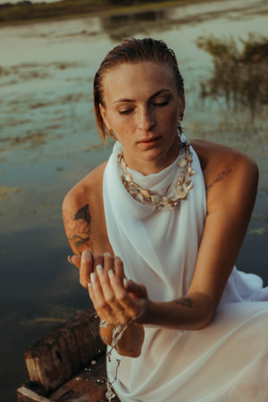 portrait of a beautiful young woman, with freckles and green eyes. a beautiful sunset light. athletic body, in a boat, against the background of waterの写真素材
