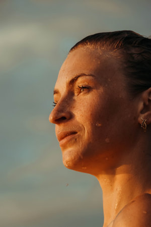 portrait of a beautiful young woman in the water, with freckles and green eyes. beautiful sunset...