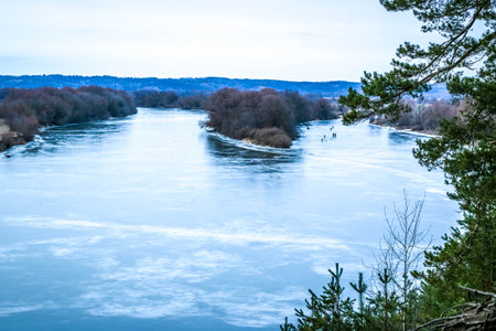 Frozen river covered with snow and ice, top view. Sandy hill with pine trees. Winter forest and river, snowy nature. Winter frosty day. beautiful ice textureの写真素材