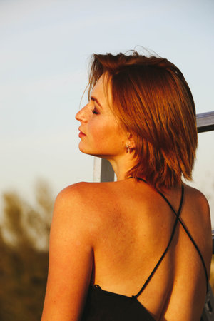 Portrait of a beautiful girl with freckles close-up, the wind flutters her hair. Warm sunset light. Emotional face, mobile facial expressions.の写真素材
