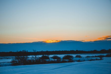 beautiful winter landscape, sunset with clouds, forest in the distance, field and trees all in the snow, frosty sunny evening, Ukraineの写真素材
