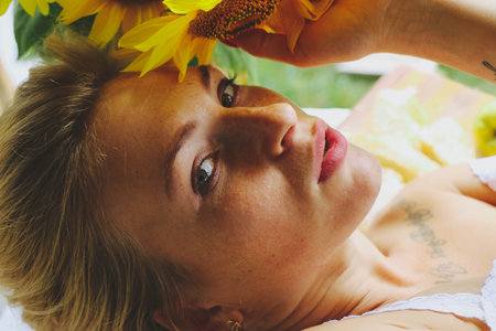portrait Beautiful young sexy woman, with short blond hair, European, sensually sniffs a sunflower...