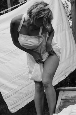 Dried laundry. Young beautiful sexy woman washes clothes and hangs underwear outdoors on a sunny day with a garden. black and white photo.の写真素材