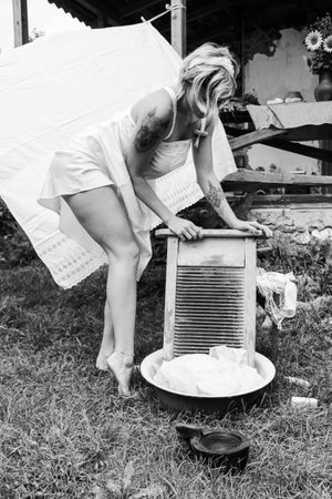 Dried laundry. Young beautiful sexy woman washes clothes and hangs underwear outdoors on a sunny day with a garden. black and white photo.の写真素材