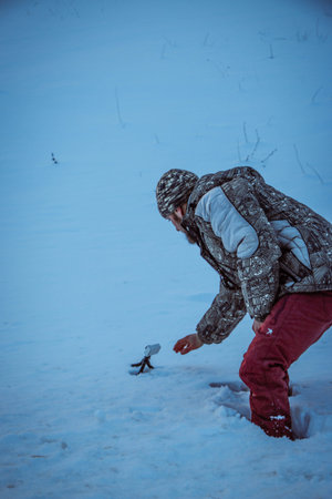 Man with phone on tripod making time-lapse photographs of winter zidio sunset. The field, road and...