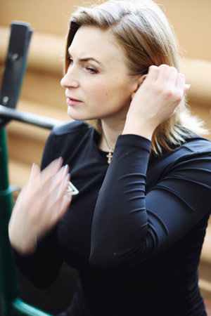 Fitness woman in sportswear sitting on a bench with dumbbell and resting in the break between sets...