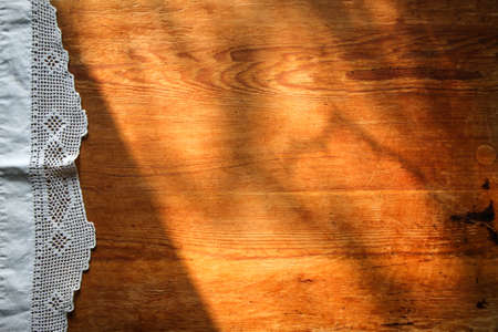 old wooden board on a white linen tablecloth and lace towel sunny natural light, shade. kitchen table top view. Beautiful retro, rustic background, free space.の写真素材