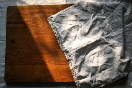 old wooden board on a white linen tablecloth and lace towel sunny natural light, shade. kitchen...