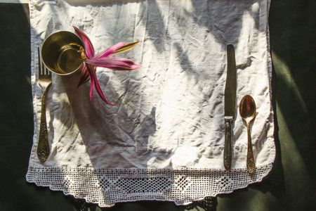 round metal plate, antique silverware, crystal glassware, white napkin on a black background of natural sunlight, shade. table setting. Beautiful retro, rustic background, free space.の写真素材