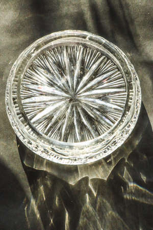 Elegant ornament transparent glassware crystal glass decoration rich design retro antique vintage object on black background, natural sunlight, glare.の写真素材