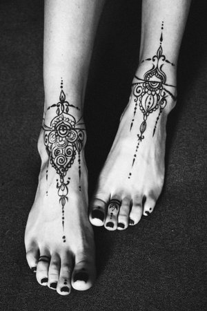 Close-up of female legs and hands with henna tattoo on the feet. Black and white photo. Gently...