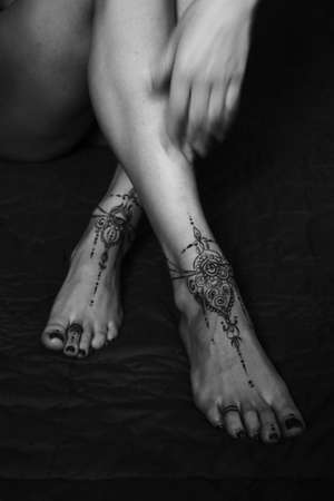 Close-up of female legs and hands with henna tattoo on the feet. Black and white photo. Gently feminine graceful decoration, respect for a woman, love and take care of yourself.の写真素材