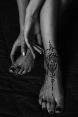 Close-up of female legs and hands with henna tattoo on the feet. Black and white photo. Gently feminine graceful decoration, respect for a woman, love and take care of yourself.の写真素材