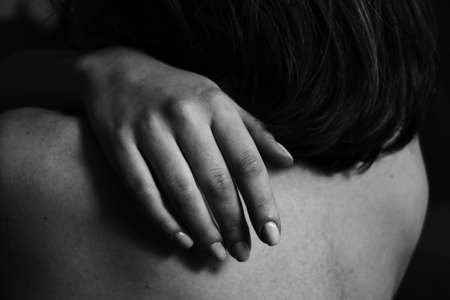 Beautiful black and white close-up photo of a woman's back and hand. Beauty, tranquility, tenderness, love and self-care. Body parts.の写真素材
