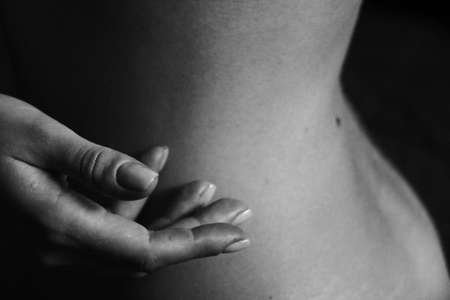 Beautiful black and white close-up photo of a woman's back and hand. Beauty, tranquility, tenderness, love and self-care. Body parts.の写真素材