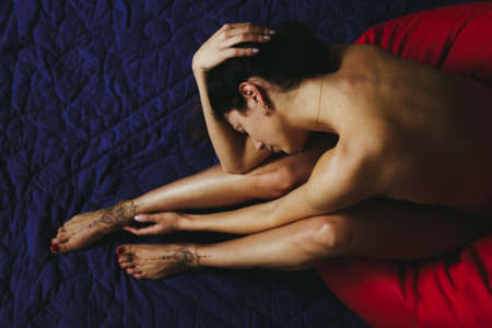 Woman top view of legs and arms with henna tattoo on legs on blue and red background. Dark hair and a beautiful back. Delicate feminine graceful decoration, respect for a woman, love and self-care.の写真素材