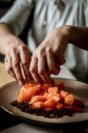 Close-up female adults shift touch orange pumpkin and raisins, prepare food in their home kitchen, normal home natural light process, selective sharpening.の写真素材