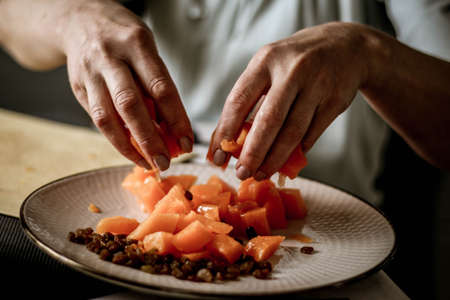 Close-up female adults shift touch orange pumpkin and raisins, prepare food in their home kitchen, normal home natural light process, selective sharpening.の写真素材