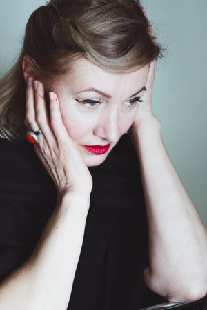 Elegant blonde beautiful middle-aged lady posing smiling at the camera. Retro makeup and hairstyle, red lips. Attractive woman.の写真素材