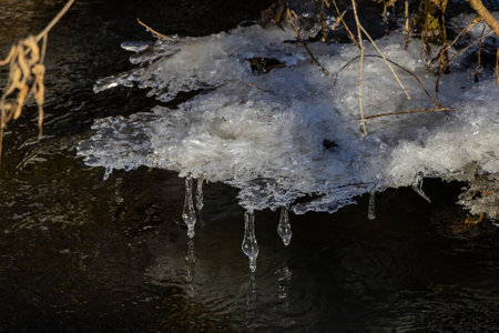 frosty ice over water. Winter Cold River, due to which ice, icicles, patterns formed. Sunny day, glare, radiation. Beautiful natural background, natural texture.の写真素材