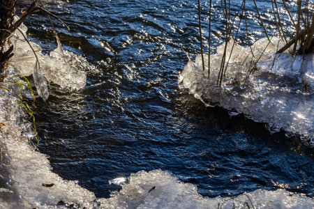 frosty ice over water. Winter Cold River, due to which ice, icicles, patterns formed. Sunny day, glare, radiation. Beautiful natural background, natural texture.の写真素材