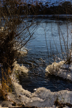 frosty ice over water. Winter Cold River, due to which ice, icicles, patterns formed. Sunny day, glare, radiation. Beautiful natural background, natural texture.の写真素材