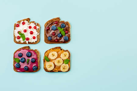 Variety of sweet sandwiches with peanut butter, chocolate butter, berry could, cream cheese, decorated with bananas, berries, mint.の写真素材