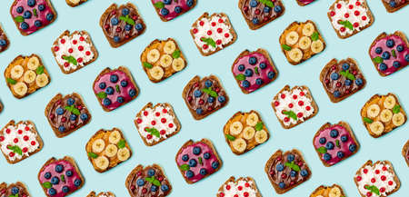 Pattern with set of different sweet sandwiches: with chocolate butter, peanut butter, soft cheese, berry curd, decorated with fruits and berries.  Light blue background. Top view. Flat lay.の写真素材