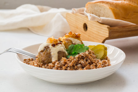 Buckwheat porridge with chicken meatballs, fried onions and sour cream, salad and sliced bread on...