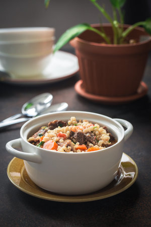 Homemade beef and barley soup. Kitchen background.