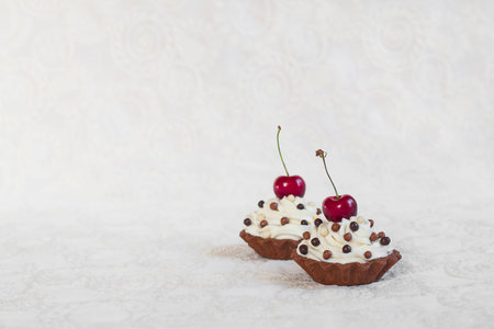Homemade tartlets with cream cheese and berries on white background.