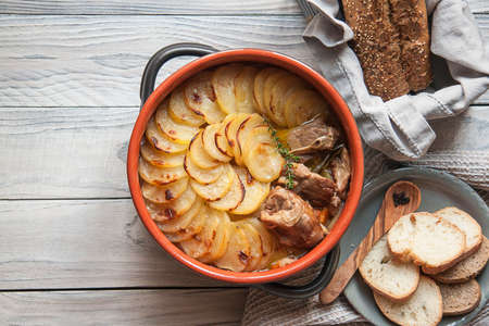 Homemade Lancashire hotpot on a light background - a stew consists of lamb, onion, carrot, Worcestershire sauce, topped with sliced potatoes, bay leaves, thyme and baked in a heavy pot on a low heat.の写真素材