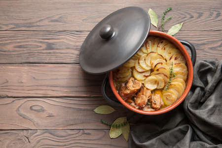 Homemade Lancashire hotpot on wooden background - a stew consists of lamb, onion, carrot, Worcestershire sauce, topped with sliced potatoes, bay leaves, thyme and baked in a heavy pot on a low heat.の写真素材