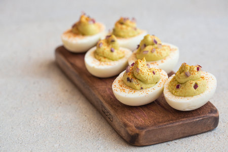 Deviled eggs with  maionese, mustard, chopped red onion and paprika on wood board. Appetizer. Copy space.の写真素材