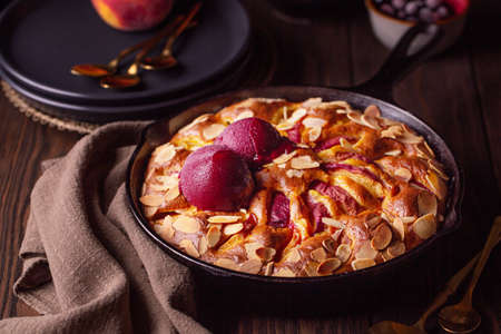 Homemade fruit cake with peaches, berries and almonds with berry sorbet on top. Dark mood photo. Horizontal image.の写真素材