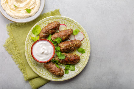 Beef koftas with yogurt, fresh coriander and hummus. Grey background.