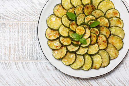 Close-up of roasted young zucchini on white wooden table. Top view, copy space.の写真素材