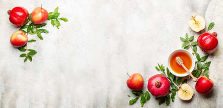 Rosh hashanah, greeting banner with symbols of Jewish New Year holiday pomegranate, honey and apples. Traditional symbols on light stone background. Copy space.の写真素材