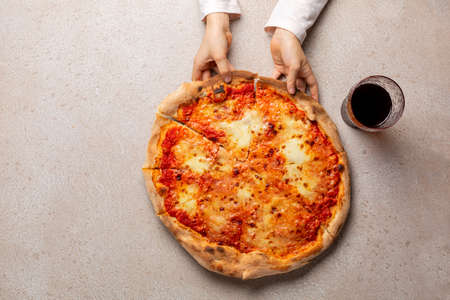 Eating pizza with mozzarella di bufala cheese. Italian made pizza Margherita on beige concrete background. Italy. Top view. Copy space.の写真素材