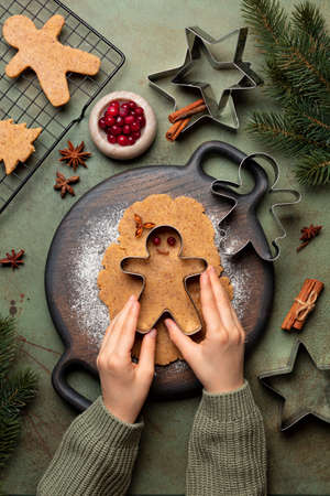 Cooking Christmas cookies, gingerbread man with cutter. Made with hazelnut butter. Christmas and New Year traditions concept, view from above, green background with fir tree brunches.の写真素材